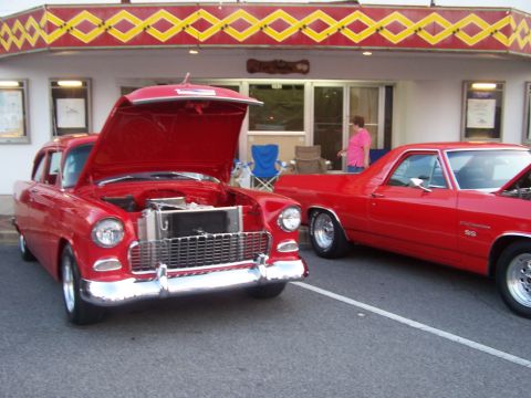 1973 Ford Ranchero - Red 1955 Chevrolet two-door sedan with its hood open at a cruise-in, showing a polished aluminum radiator and chrome grille and bumper, par…