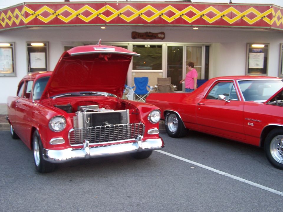 Red 1955 Chevy with hood up next to red El Camino SS at a diner cruise-in