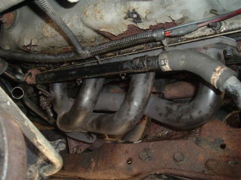 1991 Ford Bronco - Close-up view of engine components, including an exhaust manifold and hoses.