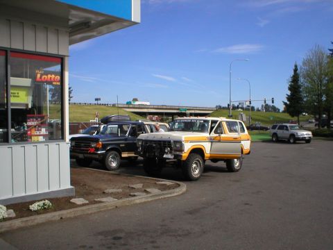 1978 Ford Bronco - Two classic Ford Broncos are parked side-by-side in a lot, with a modern SUV visible in the distance.