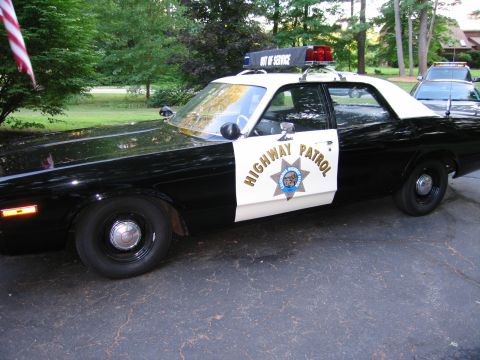 1991 Ford LTD Crown Victoria - Side view of a black-and-white California Highway Patrol sedan showing the Highway Patrol door emblem and roof light bar.