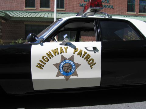 1991 Ford LTD Crown Victoria - Close-up of the white front door of a CHP-marked car showing gold HIGHWAY PATROL lettering and the California Highway Patrol seven-point st…