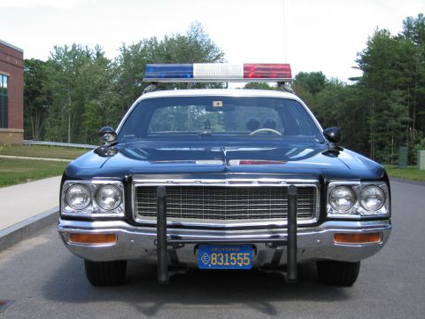 1991 Ford LTD Crown Victoria - Head-on view of a blue Dodge police car with quad headlights, roof lightbar and chrome push bar, wearing California license plate 831555.