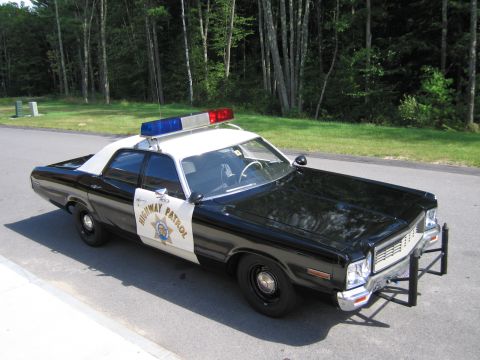 1991 Ford LTD Crown Victoria - Elevated front three-quarter view of a black-and-white HIGHWAY PATROL Dodge sedan with a chrome push bar parked on pavement beside grass.