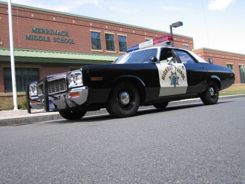 1991 Ford LTD Crown Victoria - Low-angle front view of a black-and-white HIGHWAY PATROL Dodge sedan with chrome push bar parked outside Merrimack Middle School.
