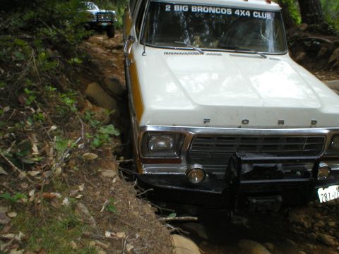 1978 Ford Bronco - Two Broncos tackle a challenging off-road path, one with a '2 BIG BRONCOS 4X4 CLUB' sticker on the windshield.