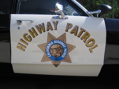 1991 Ford LTD Crown Victoria - Close-up of a white car door bearing gold HIGHWAY PATROL lettering and the California Highway Patrol seven-point star seal with chrome mirr…