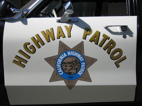 1991 Ford LTD Crown Victoria - Close-up of an off-white car door bearing gold HIGHWAY PATROL lettering and the California Highway Patrol seven-point star seal with chrome…