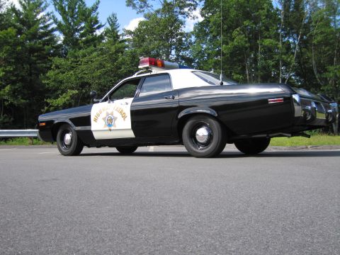 1991 Ford LTD Crown Victoria - black-and-white California Highway Patrol cruiser in rear-side view, door star emblem visible, parked by a guardrail.