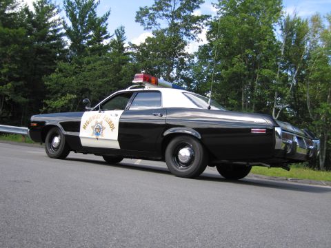 1991 Ford LTD Crown Victoria - black-and-white Highway Patrol sedan photographed from the rear three-quarter on a road lined with trees.
