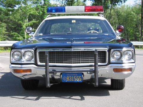 1991 Ford LTD Crown Victoria - Head-on front view of a black police car with DODGE grille lettering, dual headlights, grille guard and California plate 831555.