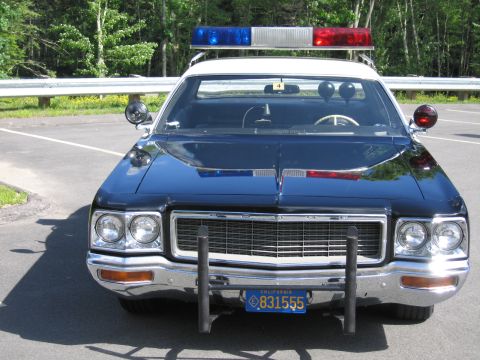 1991 Ford LTD Crown Victoria - Head-on front view of a black police car with chrome grille, push bar, roof lightbar and a California license plate.