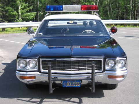 1991 Ford LTD Crown Victoria - Head-on view of a black police car with DODGE grille badge, twin headlights, grille guard and California plate 831555.