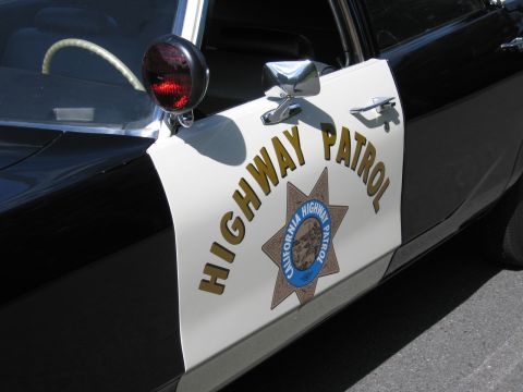 1991 Ford LTD Crown Victoria - Close-up of a car door bearing the gold CALIFORNIA HIGHWAY PATROL seven-point star emblem with a chrome spotlight above.