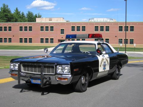 1991 Ford LTD Crown Victoria - black-and-white Highway Patrol police sedan with grille guard and California plate 831555 parked in front of a brick building.