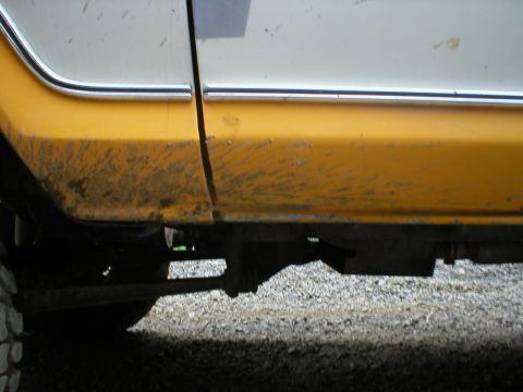 1978 Ford Bronco - Mud splatters cover the lower body panel and frame of a vehicle.