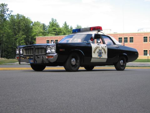 1991 Ford LTD Crown Victoria - Low front three-quarter view of a black-and-white Highway Patrol police sedan with grille guard on pavement.