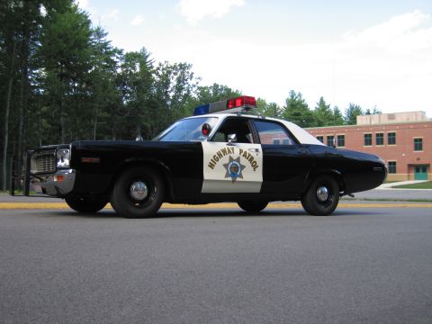 1991 Ford LTD Crown Victoria - Side view of a black-and-white Highway Patrol police sedan showing the star door emblem and roof lightbar.