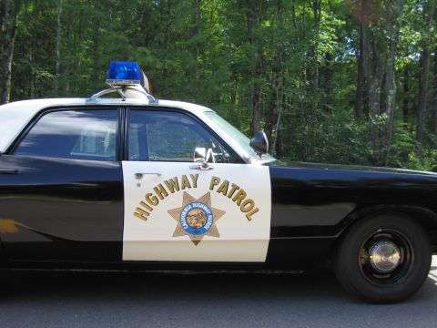 1991 Ford LTD Crown Victoria - Close-up of the California Highway Patrol gold star emblem and HIGHWAY PATROL text on a black-and-white police car door.