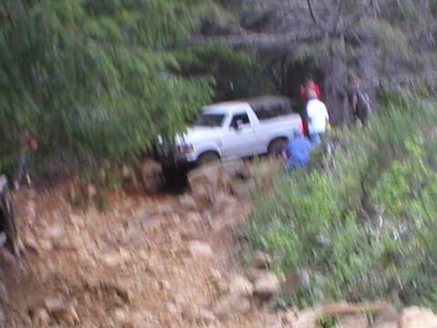 1978 Ford Bronco - A white pickup truck navigates a challenging off-road terrain.