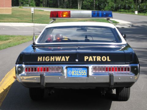1991 Ford LTD Crown Victoria - Direct rear view of a Highway Patrol police sedan with roof lightbar, whip antenna and California plate 831555.