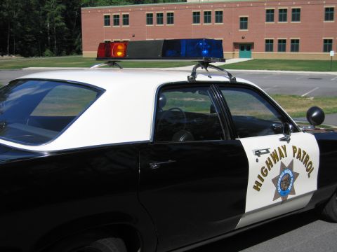 1991 Ford LTD Crown Victoria - Side rear view of a black-and-white Highway Patrol police sedan with roof lightbar, spotlight and HIGHWAY PATROL door emblem.