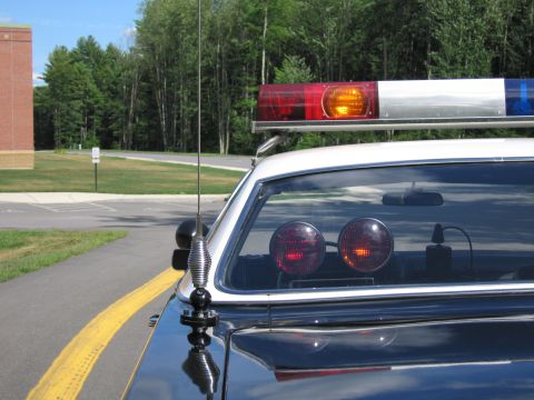 1991 Ford LTD Crown Victoria - Close-up of a police car's red-and-blue roof lightbar, whip antenna and twin red deck lights behind the rear window.