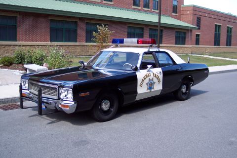 1991 Ford LTD Crown Victoria - restored black-and-white Highway Patrol sedan with a chrome push bar and roof light bar sits curbside in front of a brick building.