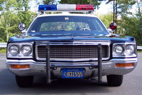1991 Ford LTD Crown Victoria - Direct front view of a black highway patrol sedan with twin headlights, roof emergency lights, and a California plate reading 831555.