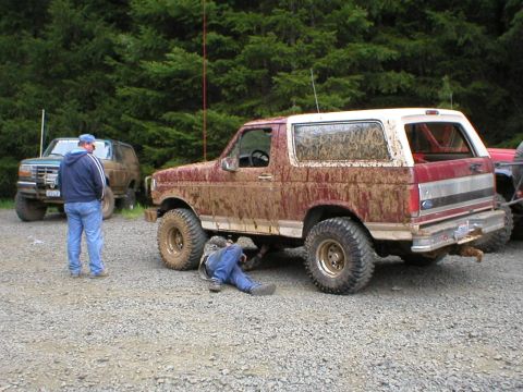 1978 Ford Bronco - A person works on a dirty Ford Bronco while another SUV sits in the background.