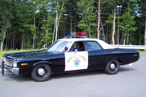 1991 Ford LTD Crown Victoria - Side profile of a black-and-white California Highway Patrol sedan showing the Highway Patrol door star and roof emergency lightbar.
