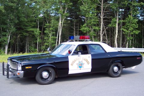 1991 Ford LTD Crown Victoria - Front-side view of a black-and-white California Highway Patrol sedan with door star emblem, chrome push bumper, and roof lightbar.