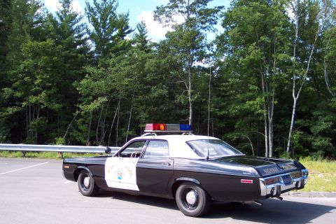 1991 Ford LTD Crown Victoria - Rear three-quarter view of a black-and-white California Highway Patrol sedan showing tail lights, roof lightbar, and a tall whip antenna.