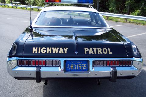 1991 Ford LTD Crown Victoria - Direct rear view of a black patrol sedan with gold HIGHWAY PATROL lettering across the trunk and California plate 831555.