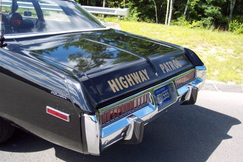 1991 Ford LTD Crown Victoria - Close rear-quarter view of a black Dodge Polara patrol sedan with gold HIGHWAY PATROL lettering and visible POLARA fender badge.