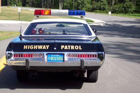 1991 Ford LTD Crown Victoria - Rear view of a black California Highway Patrol sedan with gold trunk lettering, roof emergency lights, and California plate 831555.
