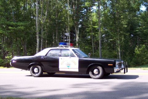 1991 Ford LTD Crown Victoria - Side-front view of a black-and-white California Highway Patrol sedan with chrome push bumper, door star, and roof emergency lights on a roa…