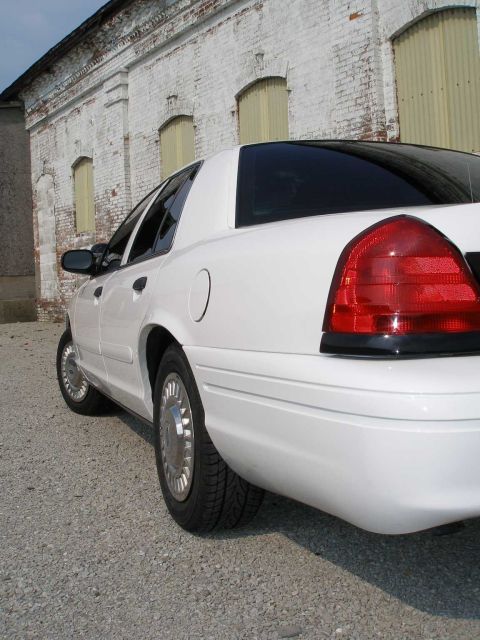 2001 Ford Crown Victoria - Rear view of a white 2001 Ford Crown Victoria parked in front of a brick building.