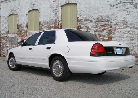 2001 Ford Crown Victoria - White 2001 Ford Crown Victoria sedan parked in front of a brick building.