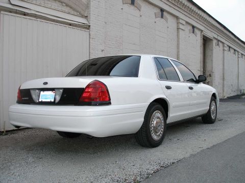 2001 Ford Crown Victoria - Rear view of a white 2001 Ford Crown Victoria parked outside a warehouse.