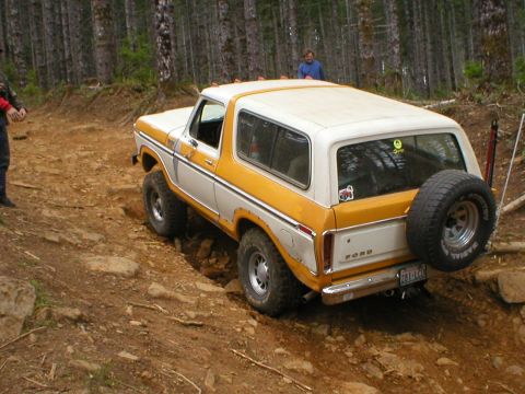 1978 Ford Bronco - A 1978 Ford Bronco navigates a challenging off-road course in a wooded area.