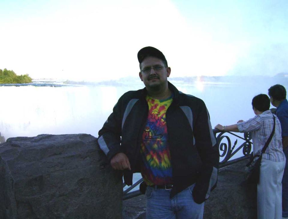 Person standing near a body of water with other people in the background