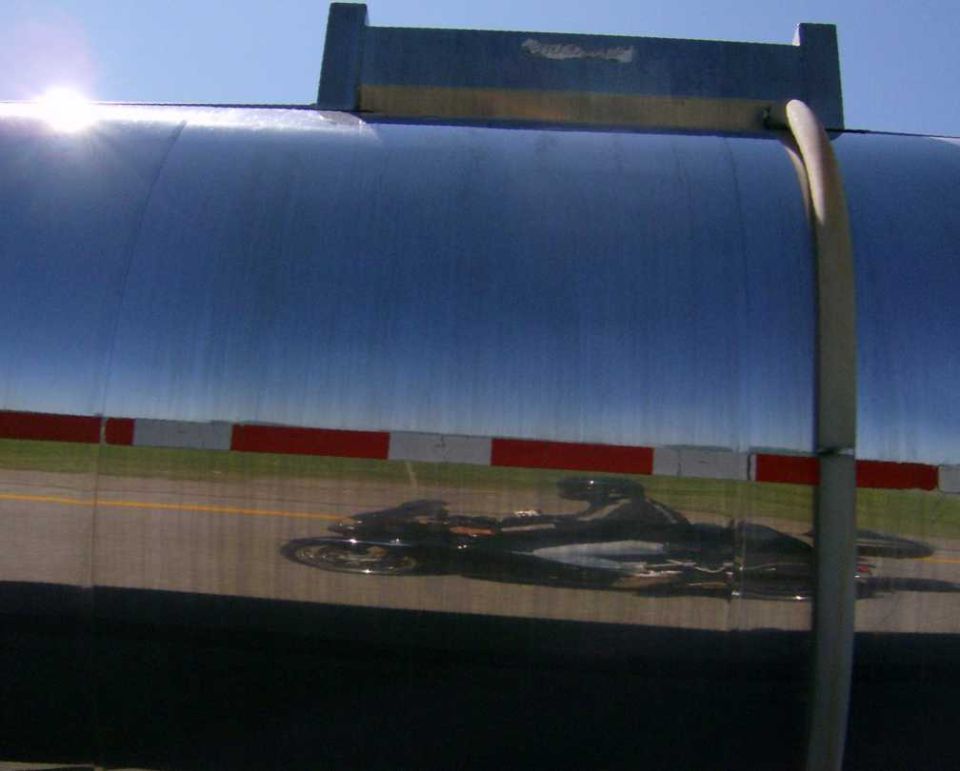 Street sign against a blue sky with a distant train on tracks
