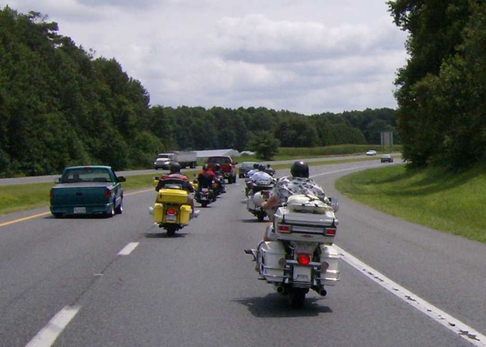 Motorcycle convoy on highway with a green pickup truck in the foreground