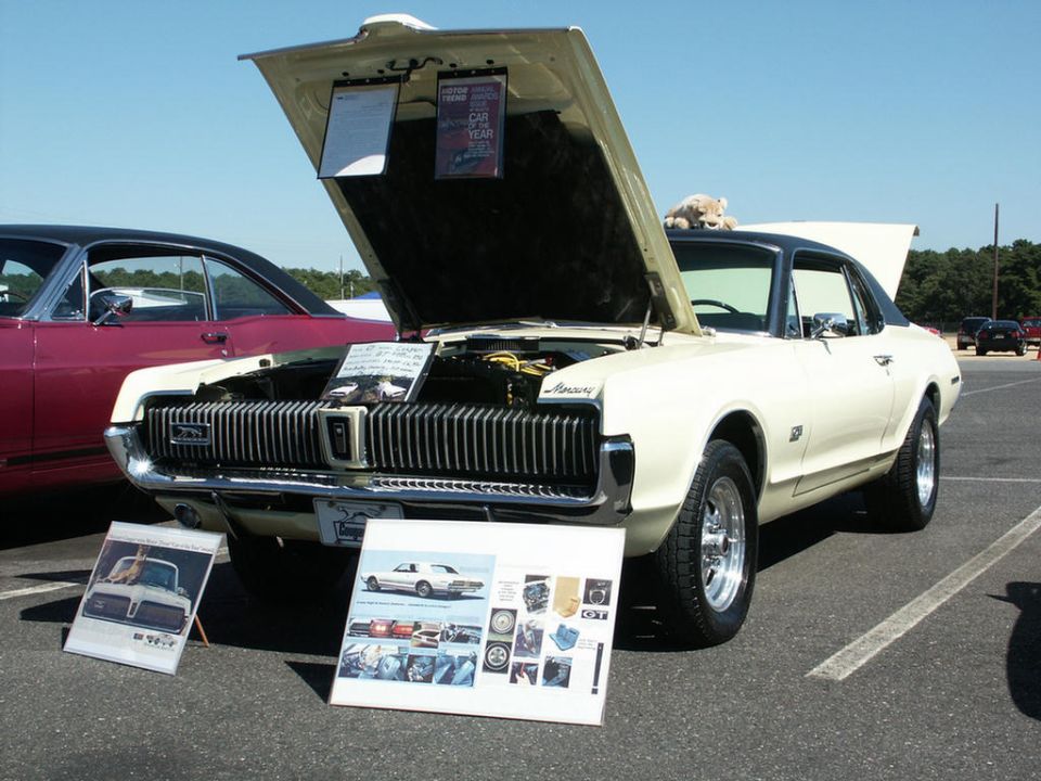 Cream 1967 Mercury Cougar with hood open, black vinyl roof, and chrome grille