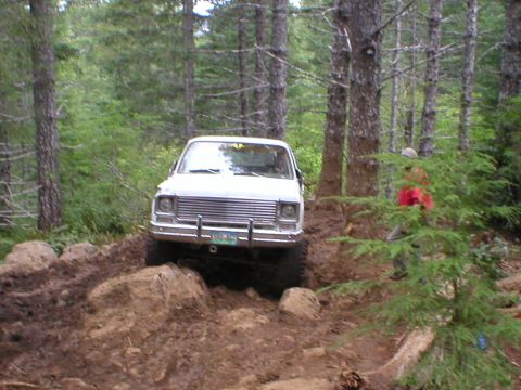 1978 Ford Bronco - A white pickup truck navigates a challenging off-road course with mud and rocks.