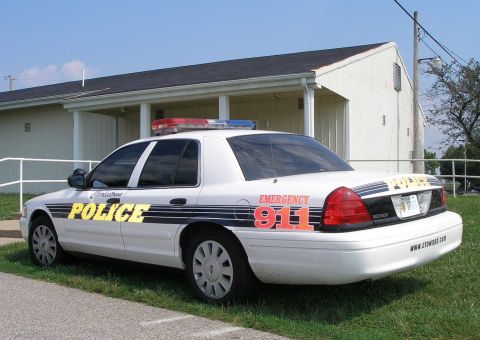1998 Ford Crown Victoria - Side view of a 1998 Ford Crown Victoria police car with emergency lights and markings.