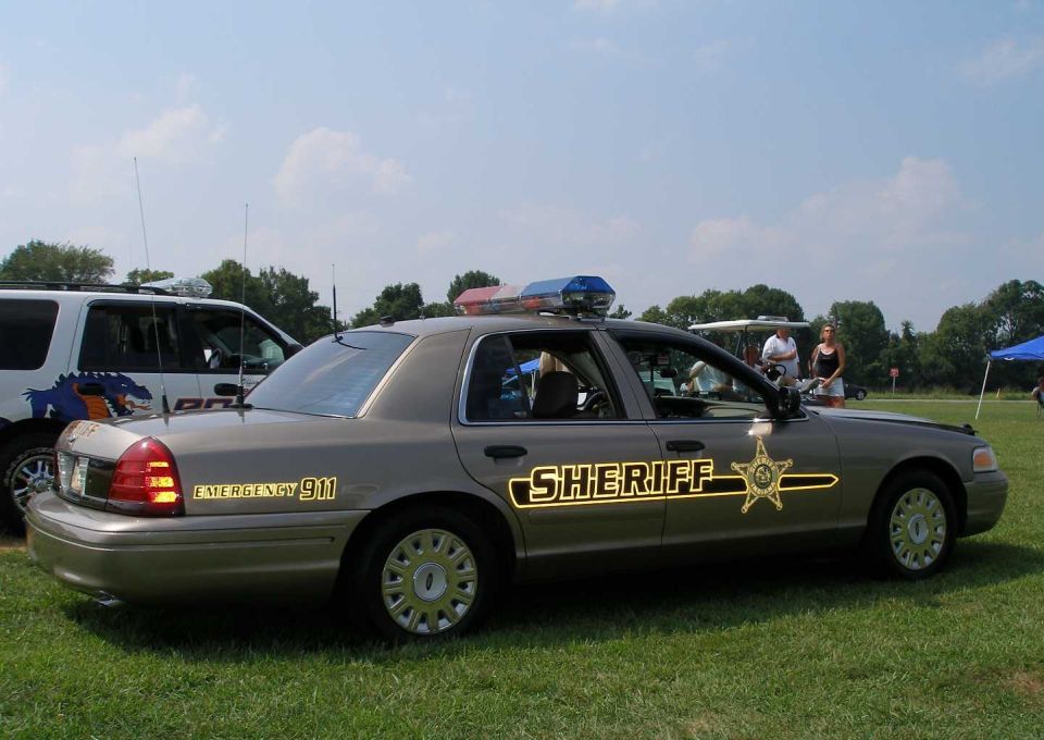 Gray Ford Crown Victoria Sheriff cruiser, side profile with star decal and light bar