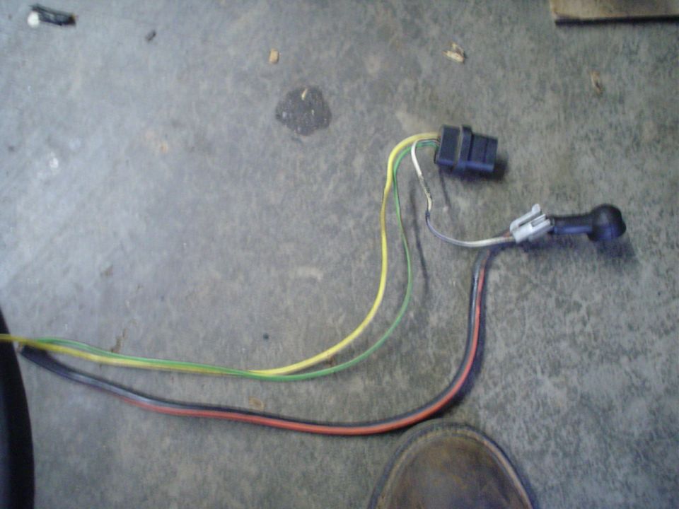 Wiring harness with black connector and a separate black sensor/connector piece, lying on a concrete floor