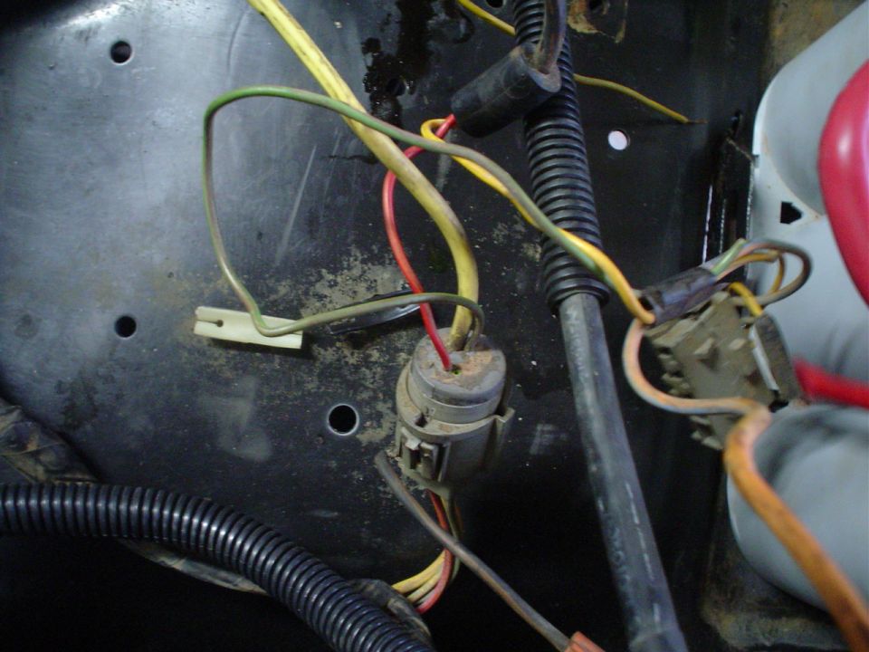 Close-up of a vehicle's electrical wiring harness with multiple colored wires connected to a connector